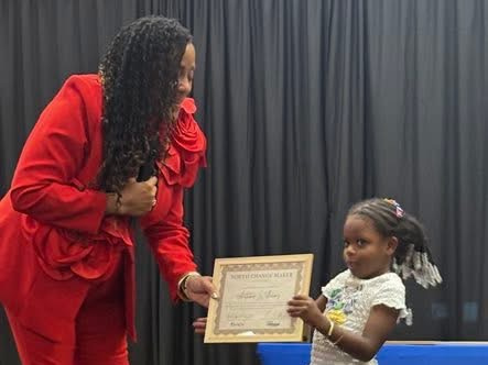 Dr. Lisa Burrell presenting a certificate to a young girl at the Why Wait? Youth Event